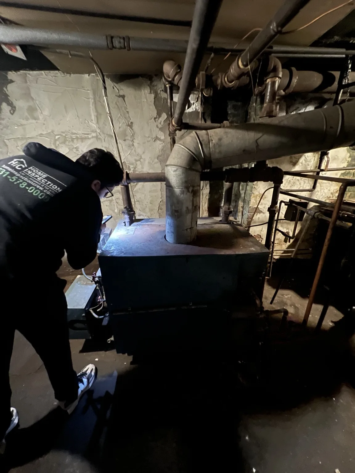 Home Inspection Crew inspector evaluating heating equipment in a basement